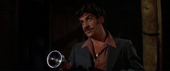 Movie still from “The Getaway” (1972), directed by Sam Peckinpah – A man with a mustache holding a camera; Medium shot, Low angle