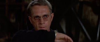 Movie still from “The Getaway” (1972), directed by Sam Peckinpah – A person wearing glasses and holding something; Close Up shot, Over the shoulder angle