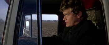 Movie still from “The Getaway” (1972), directed by Sam Peckinpah – A man sitting in the driver's seat of a truck; Close Up shot, Over the shoulder angle