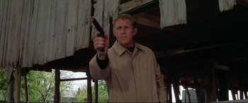 Movie still from “The Getaway” (1972), directed by Sam Peckinpah – A man in a trench coat holding a gun in his hand; Medium shot, Low angle