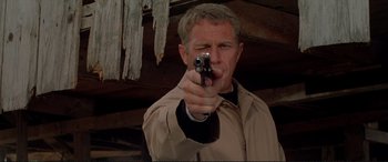 Movie still from “The Getaway” (1972), directed by Sam Peckinpah – A man holding a gun pointed at the camera; Close Up shot, Low angle
