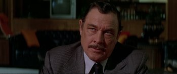 Movie still from “The Getaway” (1972), directed by Sam Peckinpah – An older man in a suit and tie looking to his left; Close Up shot, Low angle