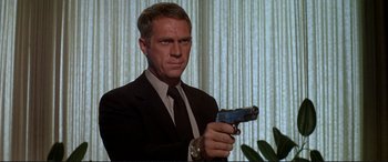 Movie still from “The Getaway” (1972), directed by Sam Peckinpah – A man in a suit and tie holding a gun; Medium shot, Low angle