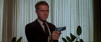 Movie still from “The Getaway” (1972), directed by Sam Peckinpah – A man in a suit and tie holding a gun; Medium shot, Low angle