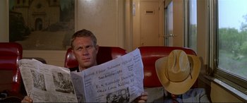 Movie still from “The Getaway” (1972), directed by Sam Peckinpah – A man sitting on a red couch reading a newspaper; Close Up shot, Over the shoulder angle