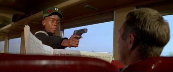 Movie still from “The Getaway” (1972), directed by Sam Peckinpah – A man holding a gun in his hand while sitting in a car; Close Up shot, Over the shoulder angle