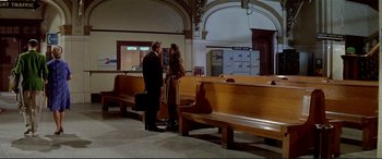 Movie still from “The Getaway” (1972), directed by Sam Peckinpah – A man and a woman standing next to each other in front of benches; Wide shot, High angle