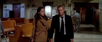 Movie still from “The Getaway” (1972), directed by Sam Peckinpah – A man and a woman holding hands while standing next to each other; Medium shot, Low angle