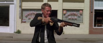 Movie still from “The Getaway” (1972), directed by Sam Peckinpah – A man in a suit and tie holding a gun; Medium shot, Low angle
