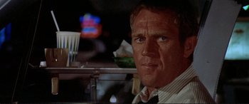 Movie still from “The Getaway” (1972), directed by Sam Peckinpah – A man sitting at a table in front of drinks; Close Up shot, Over the shoulder angle