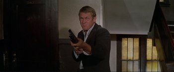 Movie still from “The Getaway” (1972), directed by Sam Peckinpah – A man holding a gun in his hand; Medium shot, Low angle