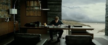 Movie still from “The Ghost Writer” (2010), directed by Roman Polanski – A man sitting at a table in front of a window; Wide shot, Over the shoulder angle