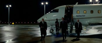 Movie still from “The Ghost Writer” (2010), directed by Roman Polanski – A group of men standing on a tarmac next to an airplane; Wide shot, High angle