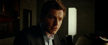 Movie still from “The Ghost Writer” (2010), directed by Roman Polanski – A man in a suit and tie looking at the camera; Close Up shot, Over the shoulder angle