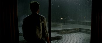 Movie still from “The Ghost Writer” (2010), directed by Roman Polanski – A man standing in the rain looking out of a window; Wide shot, Over the shoulder angle