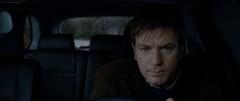 Movie still from “The Ghost Writer” (2010), directed by Roman Polanski – A man sitting in the back seat of a car; Close Up shot, Over the shoulder angle