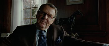 Movie still from “The Ghost Writer” (2010), directed by Roman Polanski – An older man wearing glasses and a suit and tie; Close Up shot, Over the shoulder angle