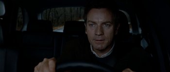 Movie still from “The Ghost Writer” (2010), directed by Roman Polanski – A person sitting in a car holding a steering wheel; Close Up shot, Over the shoulder angle