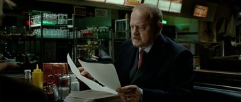 Movie still from “The Ghost Writer” (2010), directed by Roman Polanski – A man in a suit and tie looking at papers; Medium shot, Over the shoulder angle