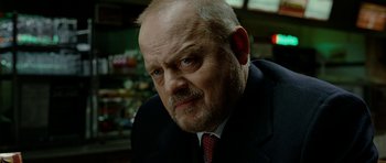 Movie still from “The Ghost Writer” (2010), directed by Roman Polanski – An older man in a black suit and a red neck tie; Close Up shot, Low angle