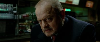 Movie still from “The Ghost Writer” (2010), directed by Roman Polanski – An older man in a black suit and red neck tie; Close Up shot, Over the shoulder angle
