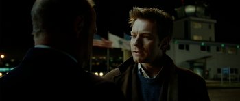 Movie still from “The Ghost Writer” (2010), directed by Roman Polanski – A man in a brown jacket talking to another man in a blue sweater; Close Up shot, Over the shoulder angle