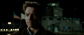 Movie still from “The Ghost Writer” (2010), directed by Roman Polanski – A person wearing a jacket with buildings in the background; Close Up shot, Over the shoulder angle