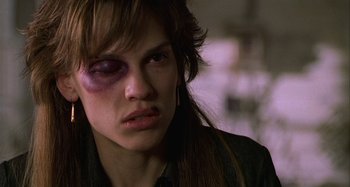 Movie still from “The Gift” (2000), directed by Sam Raimi – A young woman with a bruised eye is looking at the camera; Close Up shot, Over the shoulder angle