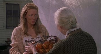 Movie still from “The Gift” (2000), directed by Sam Raimi – An older woman is holding a basket of pineapples while a younger woman looks on; Medium shot, Over the shoulder angle