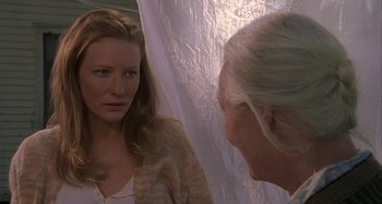Movie still from “The Gift” (2000), directed by Sam Raimi – A woman looking into a mirror while standing next to a curtain; Close Up shot, Over the shoulder angle