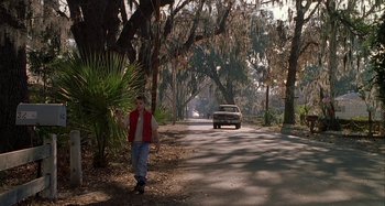 Movie still from “The Gift” (2000), directed by Sam Raimi – A man walking down a street with a car in the background; Wide shot, High angle