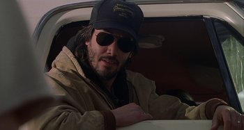 Movie still from “The Gift” (2000), directed by Sam Raimi – A man with a hat and sunglasses sitting in the driver's seat of a car; Close Up shot, Low angle