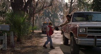 Movie still from “The Gift” (2000), directed by Sam Raimi – A man handing a baseball cap to a boy in front of a red truck; Wide shot, Over the shoulder angle