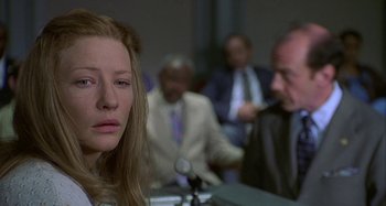 Movie still from “The Gift” (2000), directed by Sam Raimi – A woman sitting in front of a microphone in front of other people; Close Up shot, Over the shoulder angle