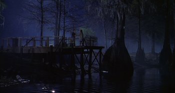Movie still from “The Gift” (2000), directed by Sam Raimi – Two people are standing on a bridge over a body of water at night; Extreme Wide shot, High angle