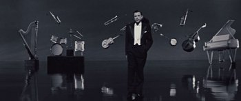 Movie still from “The Girl Can't Help It” (1956), directed by Frank Tashlin – A black and white photo of a man in a tuxedo; Wide shot, High angle