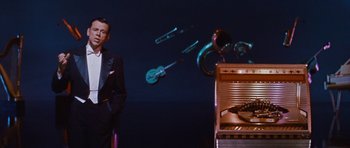 Movie still from “The Girl Can't Help It” (1956), directed by Frank Tashlin – A man standing in front of an organ with musical instruments flying in the background; Medium shot, Low angle