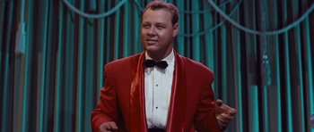 Movie still from “The Girl Can't Help It” (1956), directed by Frank Tashlin – A man in a red jacket and a bow tie; Medium shot, Low angle