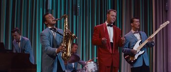 Movie still from “The Girl Can't Help It” (1956), directed by Frank Tashlin – A man in a red suit is playing the saxophone; Medium shot, Low angle
