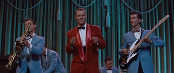 Movie still from “The Girl Can't Help It” (1956), directed by Frank Tashlin – A man in a red suit and a red tie; Medium shot, Over the shoulder angle