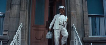 Movie still from “The Girl Can't Help It” (1956), directed by Frank Tashlin – A man in a white suit and hat holding a basket; Wide shot, Low angle