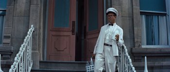 Movie still from “The Girl Can't Help It” (1956), directed by Frank Tashlin – A man in a white suit and hat holding a cup; Medium shot, Low angle