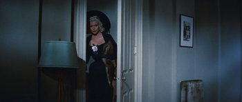 Movie still from “The Girl Can't Help It” (1956), directed by Frank Tashlin – A woman in a black dress with a black umbrella; Medium shot, Over the shoulder angle