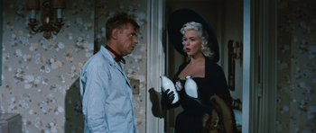 Movie still from “The Girl Can't Help It” (1956), directed by Frank Tashlin – A man and a woman holding milk jugs in a room; Medium shot, Over the shoulder angle
