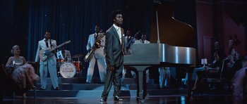 Movie still from “The Girl Can't Help It” (1956), directed by Frank Tashlin – A man in a suit holding a saxophone in front of a piano; Medium shot, Low angle