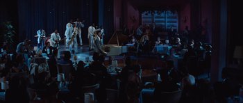 Movie still from “The Girl Can't Help It” (1956), directed by Frank Tashlin – A group of people sitting and standing around a room; Extreme Wide shot, High angle