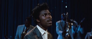 Movie still from “The Girl Can't Help It” (1956), directed by Frank Tashlin – A man in a gray suit and white shirt is singing; Close Up shot, Low angle