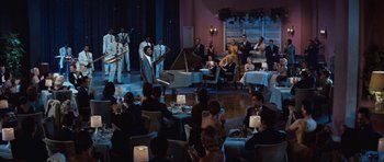 Movie still from “The Girl Can't Help It” (1956), directed by Frank Tashlin – A group of people sitting around a room with musical instruments; Extreme Wide shot, High angle