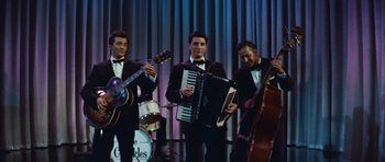 Movie still from “The Girl Can't Help It” (1956), directed by Frank Tashlin – A group of men in tuxedos playing musical instruments; Medium shot, Low angle