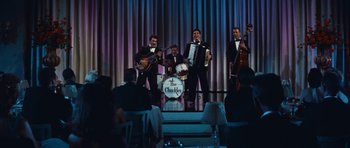 Movie still from “The Girl Can't Help It” (1956), directed by Frank Tashlin – A group of men in tuxedos on a stage with instruments; Wide shot, High angle
